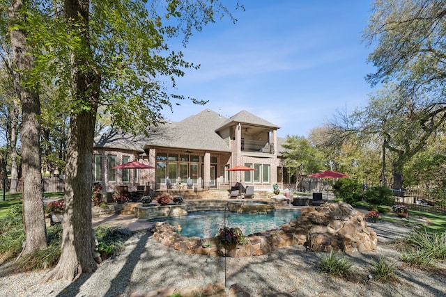 rear view of property featuring a fenced in pool, a balcony, and a patio