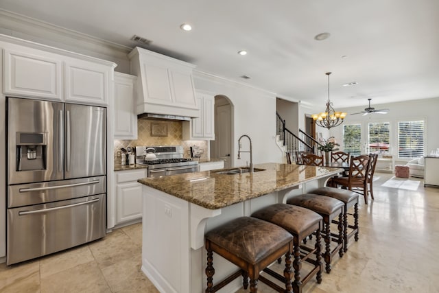 kitchen with dark stone counters, an island with sink, stainless steel appliances, and custom exhaust hood