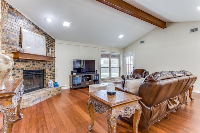 living room with a brick fireplace, lofted ceiling with beams, and hardwood / wood-style floors