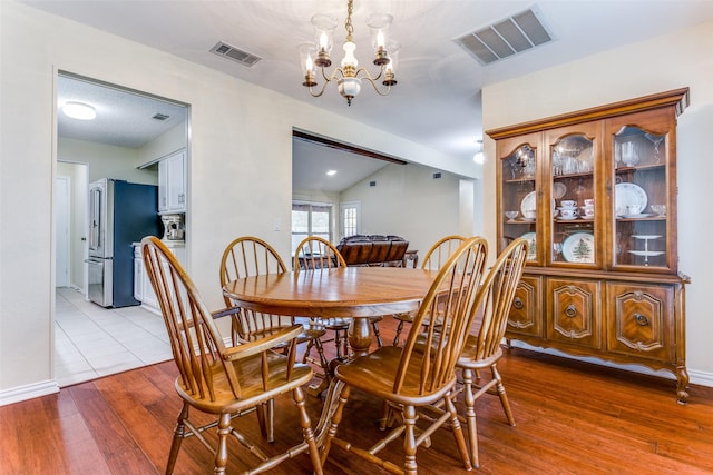 dining room with lofted ceiling, light hardwood / wood-style flooring, and a notable chandelier