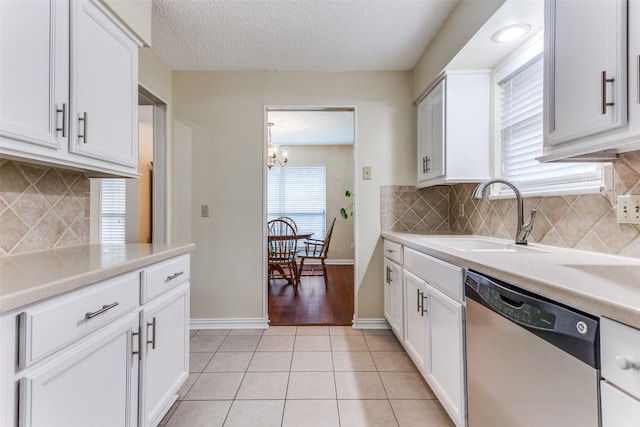 kitchen with sink, white cabinets, a chandelier, stainless steel dishwasher, and light tile patterned floors