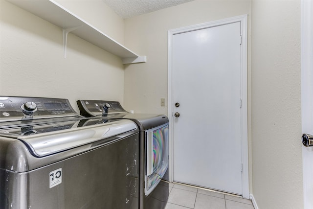 laundry room with washing machine and clothes dryer, a textured ceiling, and light tile patterned floors