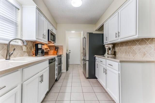 kitchen featuring white cabinets, light tile patterned floors, sink, and appliances with stainless steel finishes