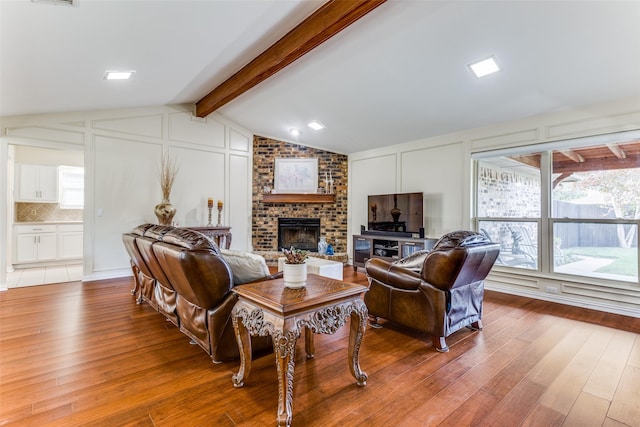 living room with a fireplace, hardwood / wood-style floors, and vaulted ceiling with beams