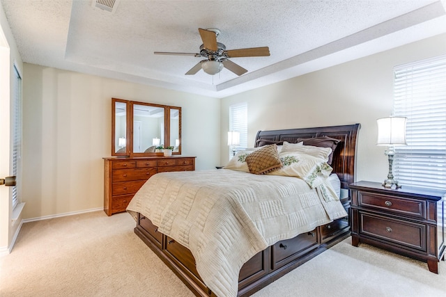 carpeted bedroom with ceiling fan, a tray ceiling, and a textured ceiling