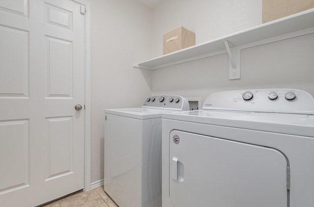 clothes washing area with light tile patterned floors and washer and dryer