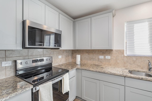 kitchen with backsplash, white cabinetry, sink, and appliances with stainless steel finishes