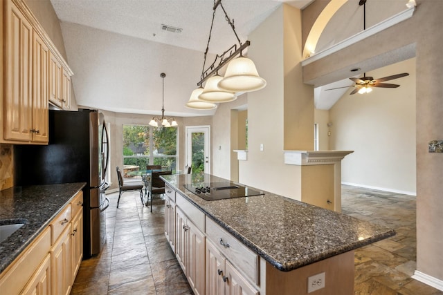 kitchen with black electric stovetop, ceiling fan with notable chandelier, a textured ceiling, decorative light fixtures, and a kitchen island