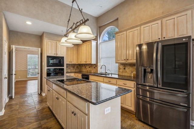 kitchen with pendant lighting, black appliances, sink, dark stone countertops, and a kitchen island