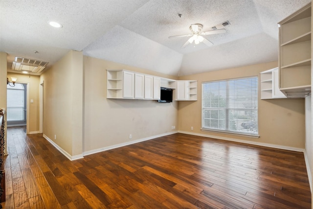 unfurnished living room with a textured ceiling, vaulted ceiling, ceiling fan, and dark wood-type flooring