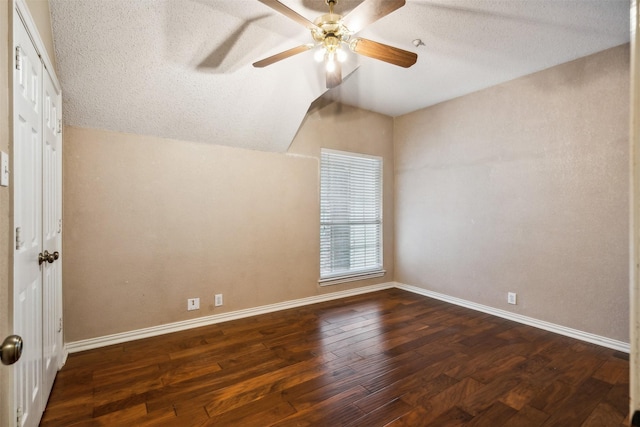 empty room with a textured ceiling, dark hardwood / wood-style floors, vaulted ceiling, and ceiling fan