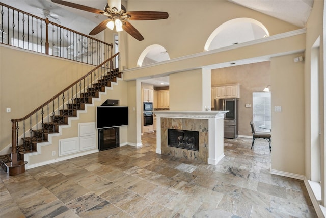 unfurnished living room with a tile fireplace, ceiling fan, and high vaulted ceiling