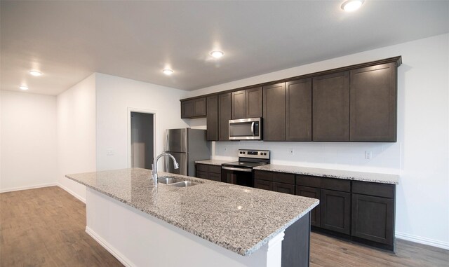 kitchen featuring a kitchen island with sink, sink, stainless steel appliances, and light hardwood / wood-style flooring