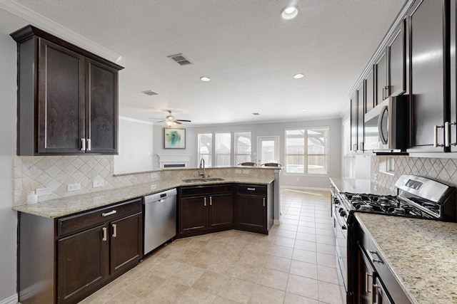 kitchen featuring sink, ceiling fan, light stone countertops, appliances with stainless steel finishes, and kitchen peninsula