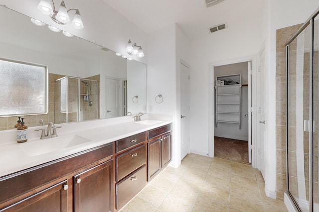 bathroom with tile patterned flooring, vanity, a shower with shower door, and an inviting chandelier