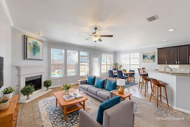 living room with light hardwood / wood-style flooring, ceiling fan, and ornamental molding