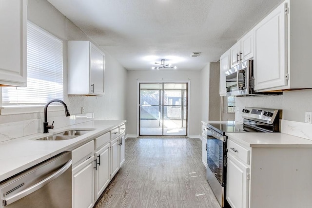 kitchen with white cabinetry, appliances with stainless steel finishes, sink, and light hardwood / wood-style flooring