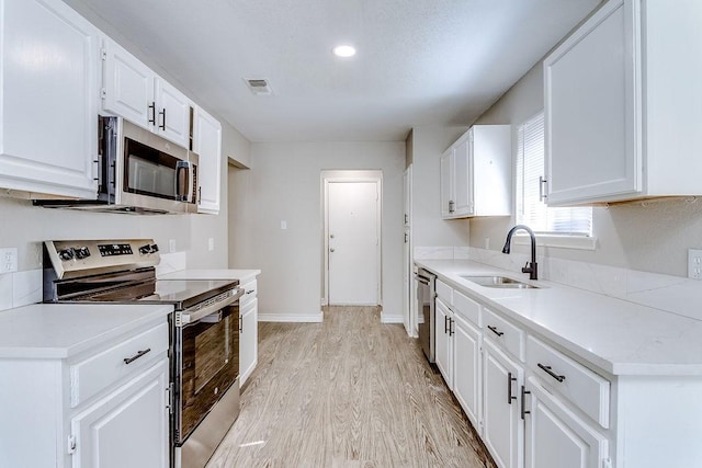 kitchen featuring white cabinetry, sink, light hardwood / wood-style floors, and appliances with stainless steel finishes