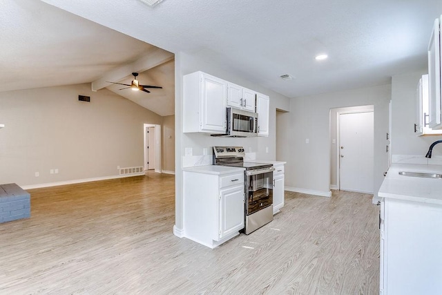 kitchen featuring appliances with stainless steel finishes, white cabinetry, sink, ceiling fan, and light hardwood / wood-style flooring