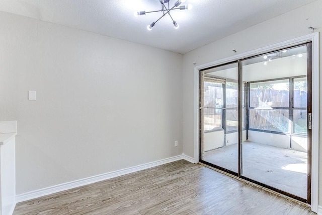 unfurnished room with a notable chandelier and light wood-type flooring