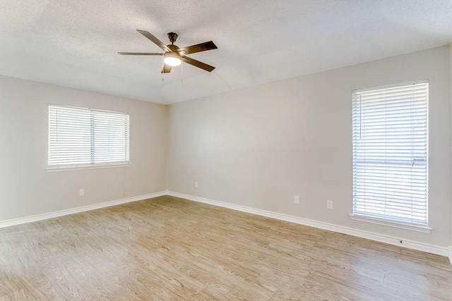 unfurnished room with a wealth of natural light, light hardwood / wood-style floors, and ceiling fan