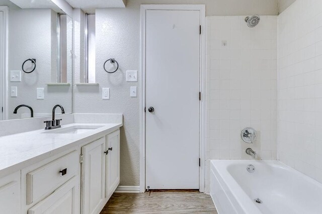 bathroom featuring tiled shower / bath, vanity, and hardwood / wood-style floors