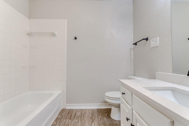 full bathroom with vanity, tiled shower / bath, hardwood / wood-style flooring, and toilet