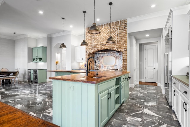 kitchen featuring green cabinets, a center island with sink, white cabinets, and wood counters