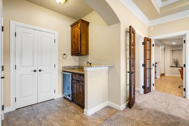 kitchen with wine cooler, light colored carpet, and ornamental molding