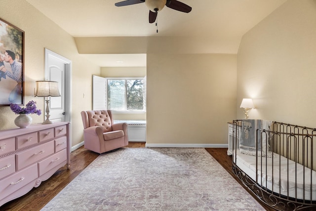 bedroom with vaulted ceiling, ceiling fan, dark hardwood / wood-style flooring, and a crib