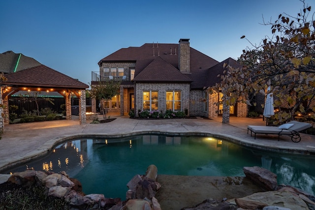 pool at dusk featuring a patio