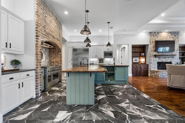 kitchen with wooden counters, dark hardwood / wood-style floors, built in appliances, a center island with sink, and white cabinets