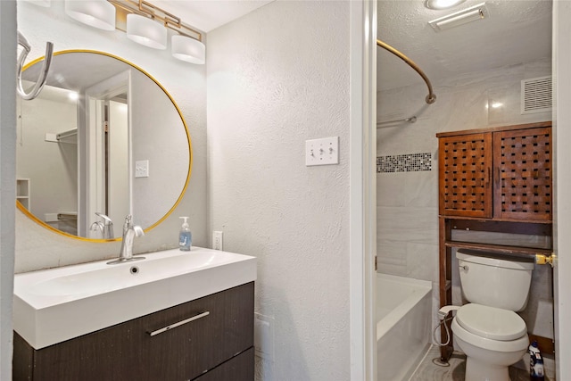 full bathroom with a textured ceiling, vanity, toilet, and tiled shower / bath