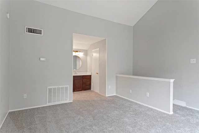 unfurnished bedroom with ensuite bathroom, light carpet, and lofted ceiling