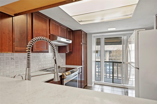 kitchen with decorative backsplash, sink, light tile patterned floors, and white refrigerator