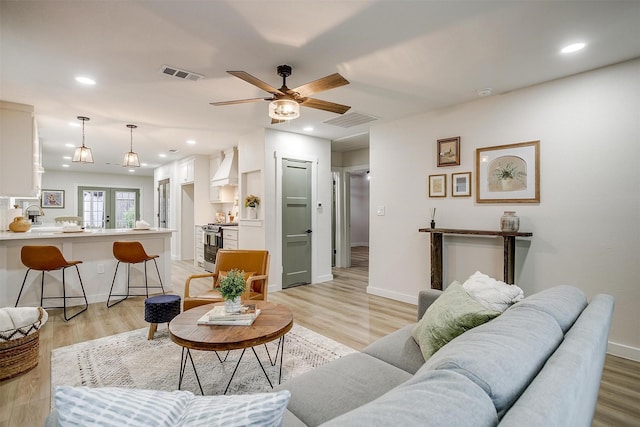 living room with ceiling fan and light hardwood / wood-style flooring