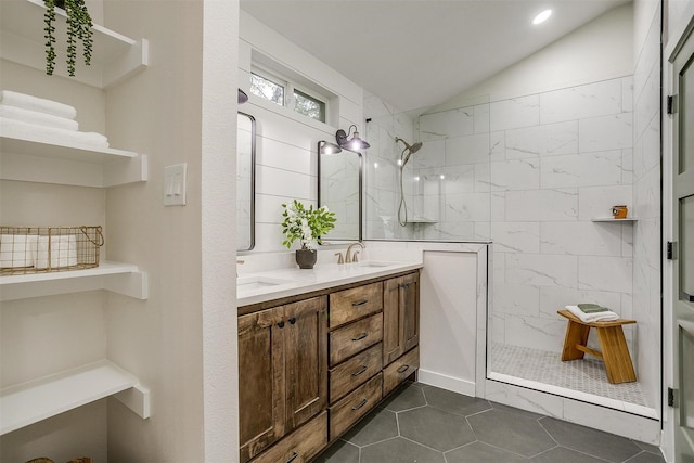 bathroom with tile patterned floors, vanity, a tile shower, and lofted ceiling