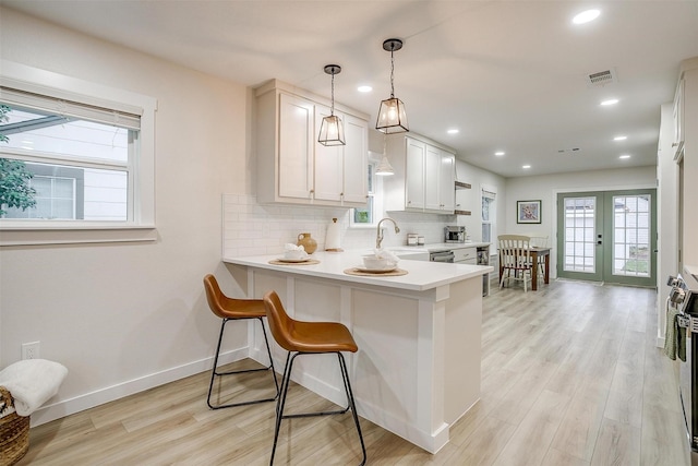 kitchen featuring french doors, kitchen peninsula, sink, decorative light fixtures, and white cabinetry