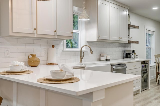 kitchen featuring wine cooler, white cabinetry, hanging light fixtures, and decorative backsplash