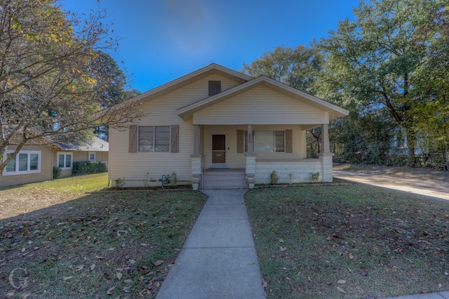 bungalow featuring covered porch and a front lawn