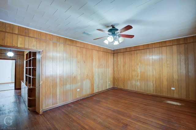 empty room with dark wood-type flooring, ceiling fan, and wood walls