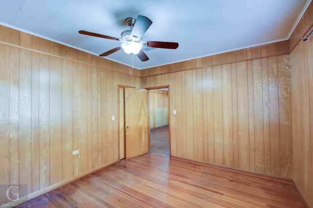 unfurnished room featuring wood-type flooring, wooden walls, and ceiling fan