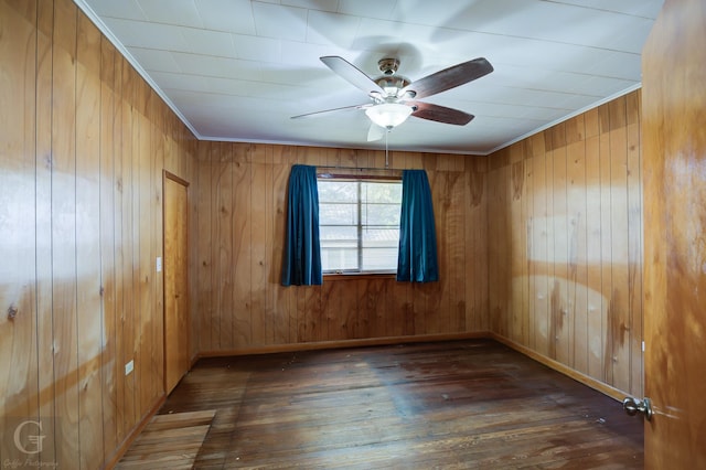 unfurnished room with ceiling fan, ornamental molding, wooden walls, and dark hardwood / wood-style flooring