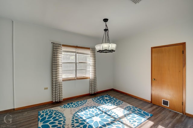 spare room with hardwood / wood-style flooring and a chandelier