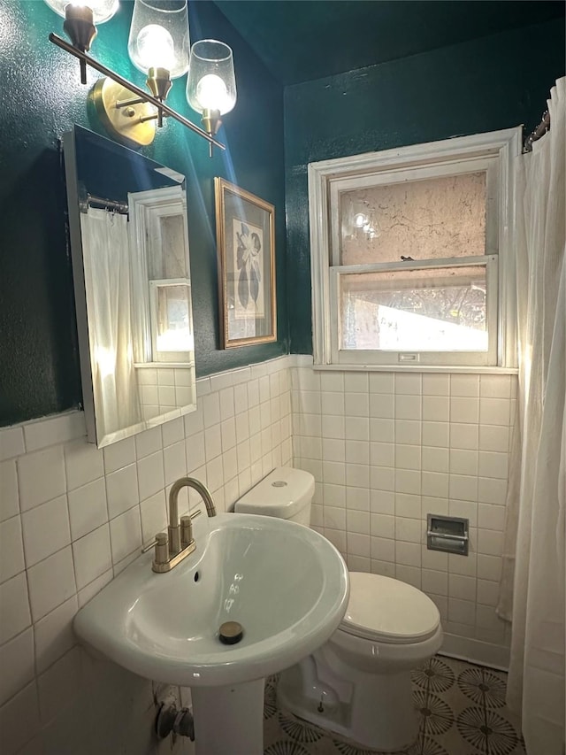 bathroom with toilet, tile walls, and sink