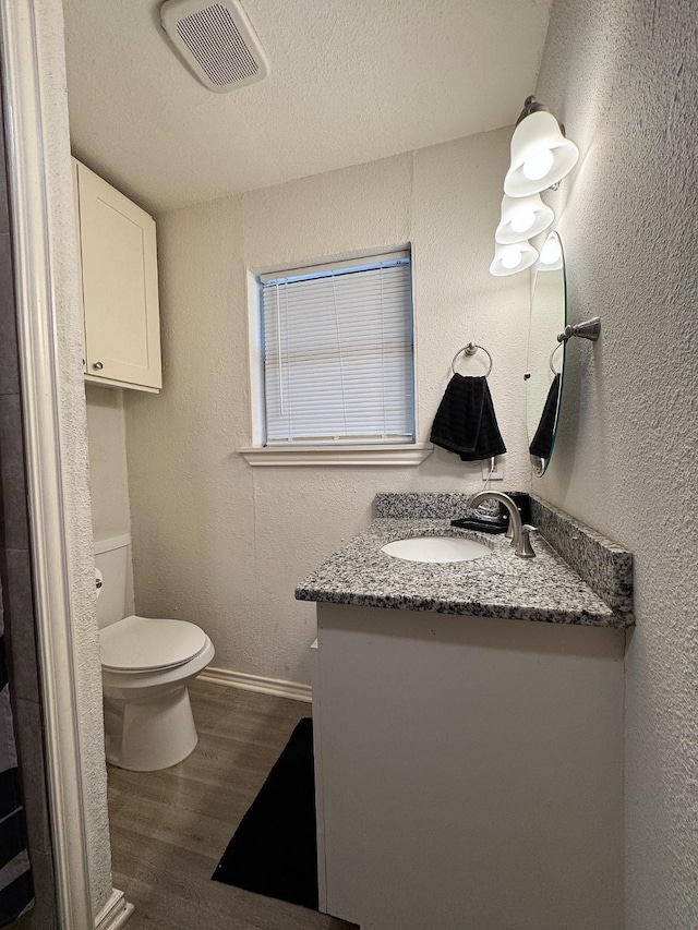 bathroom featuring hardwood / wood-style floors, vanity, toilet, and a textured ceiling