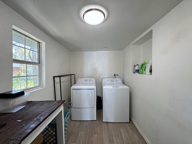 laundry room featuring washer and dryer, plenty of natural light, light hardwood / wood-style floors, and a textured ceiling