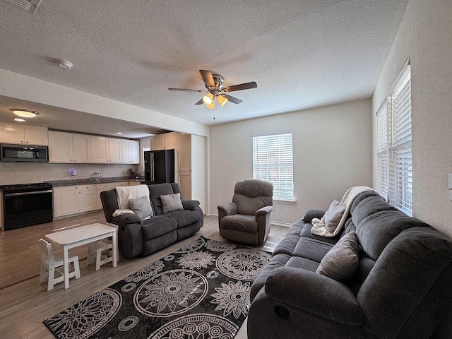 living room with hardwood / wood-style floors, a textured ceiling, and ceiling fan