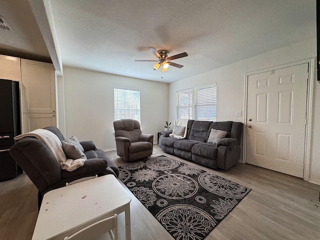 living room with hardwood / wood-style flooring, ceiling fan, and a textured ceiling