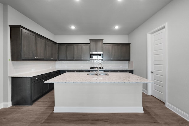 kitchen with a kitchen island with sink, sink, dark hardwood / wood-style floors, tasteful backsplash, and dark brown cabinets